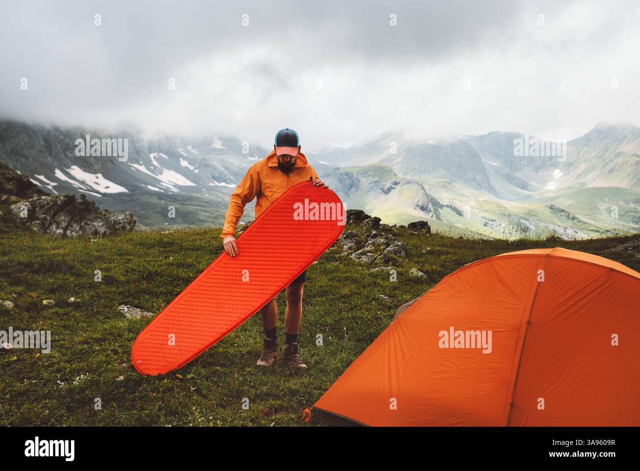 Man mountaineering with camping gear tent and sleeping pad - travel solo adventure healthy lifestyle summer active vacations trip survival climbing eq Stock Photo