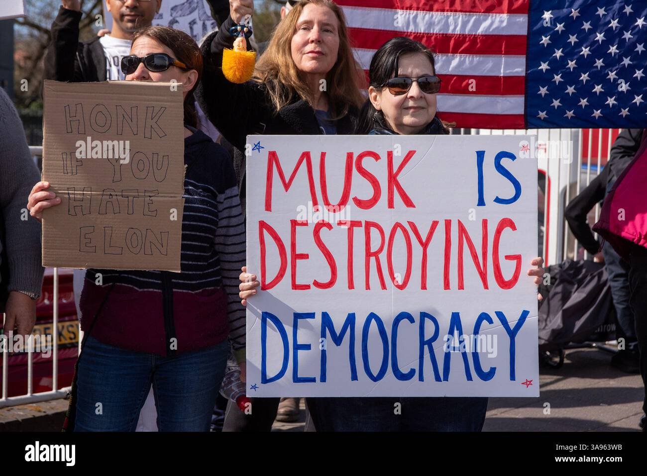 Protesters stand with their signs outside the Tesla dealership during ...
