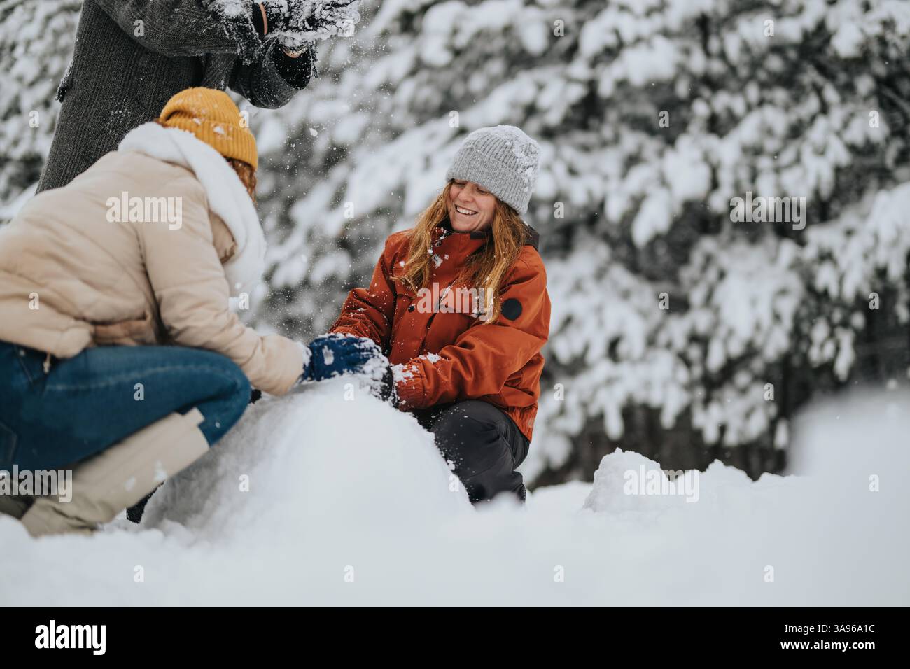 Group of friends building a snowman outdoors in a snowy forest ...