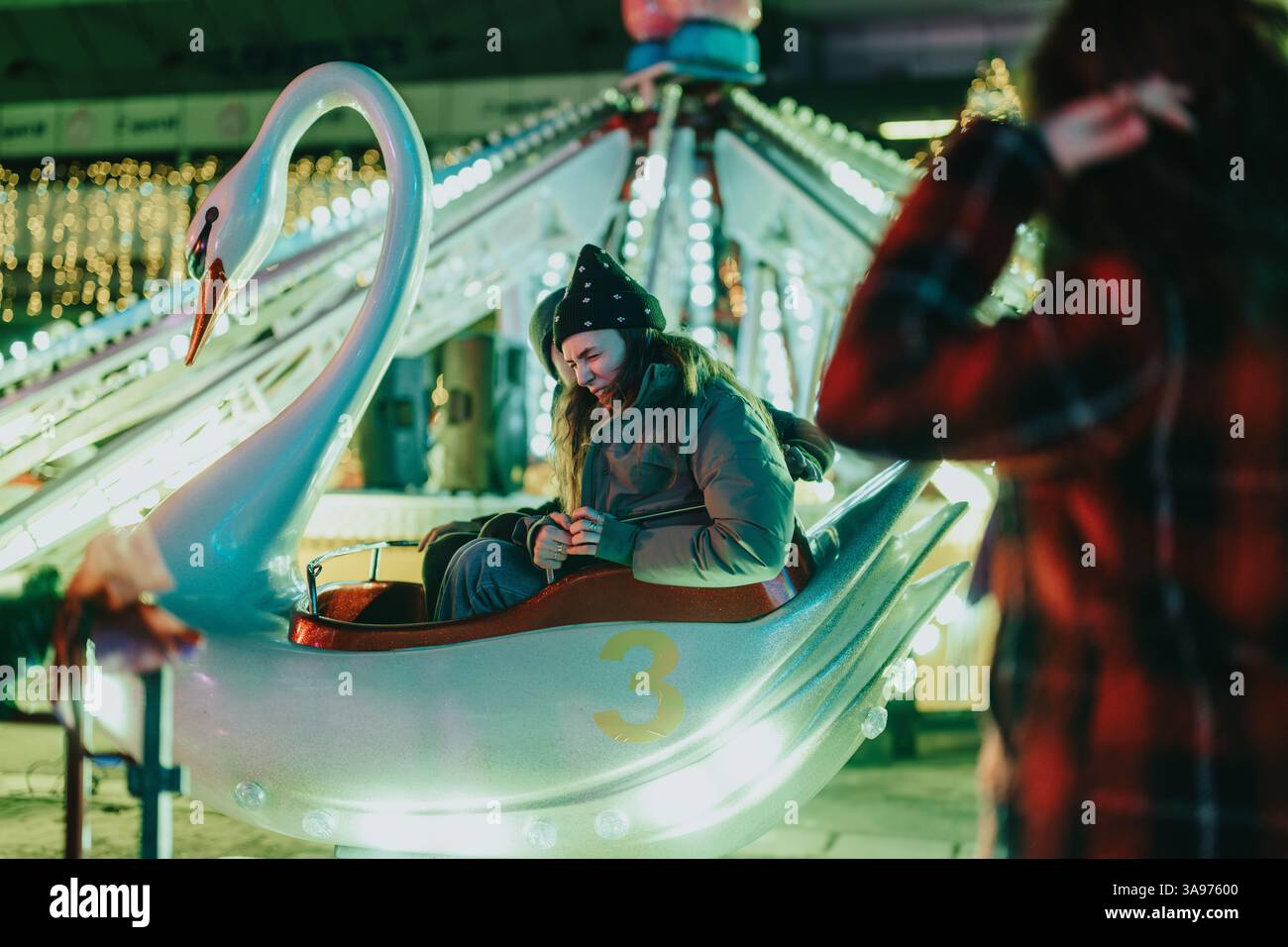 Child enjoying a swan ride at a brightly lit winter carnival Stock ...