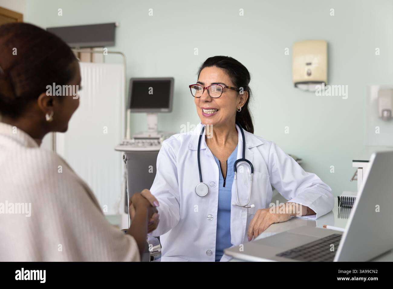 Positive doctor giving handshake to patient after consultation Stock Photo