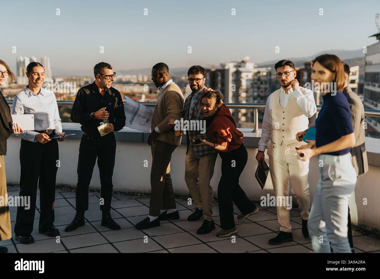 Multicultural team enjoying a sunset break on rooftop balcony Stock Photo