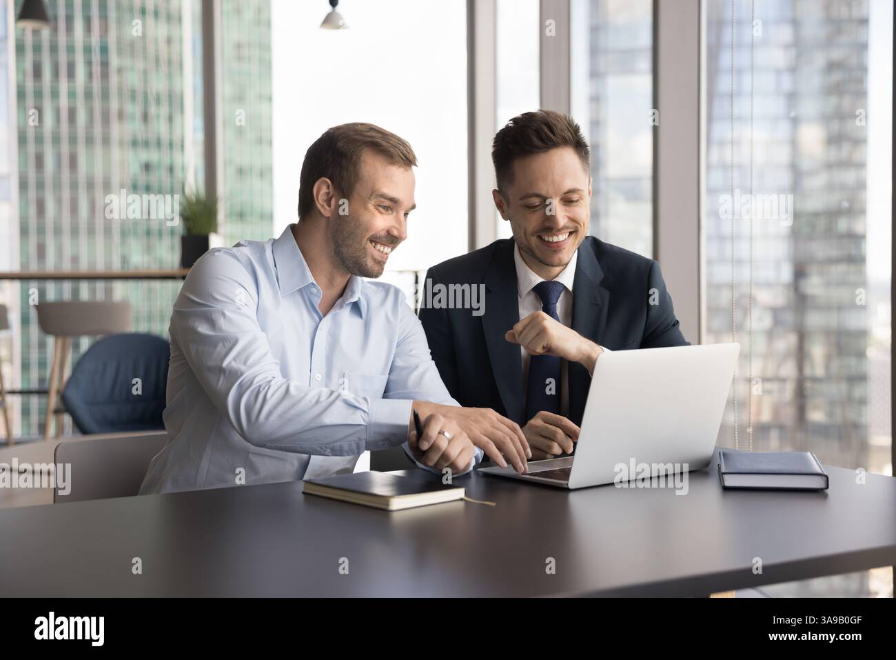 Two laughing multiethnic teammates cooperating on on-line project Stock Photo