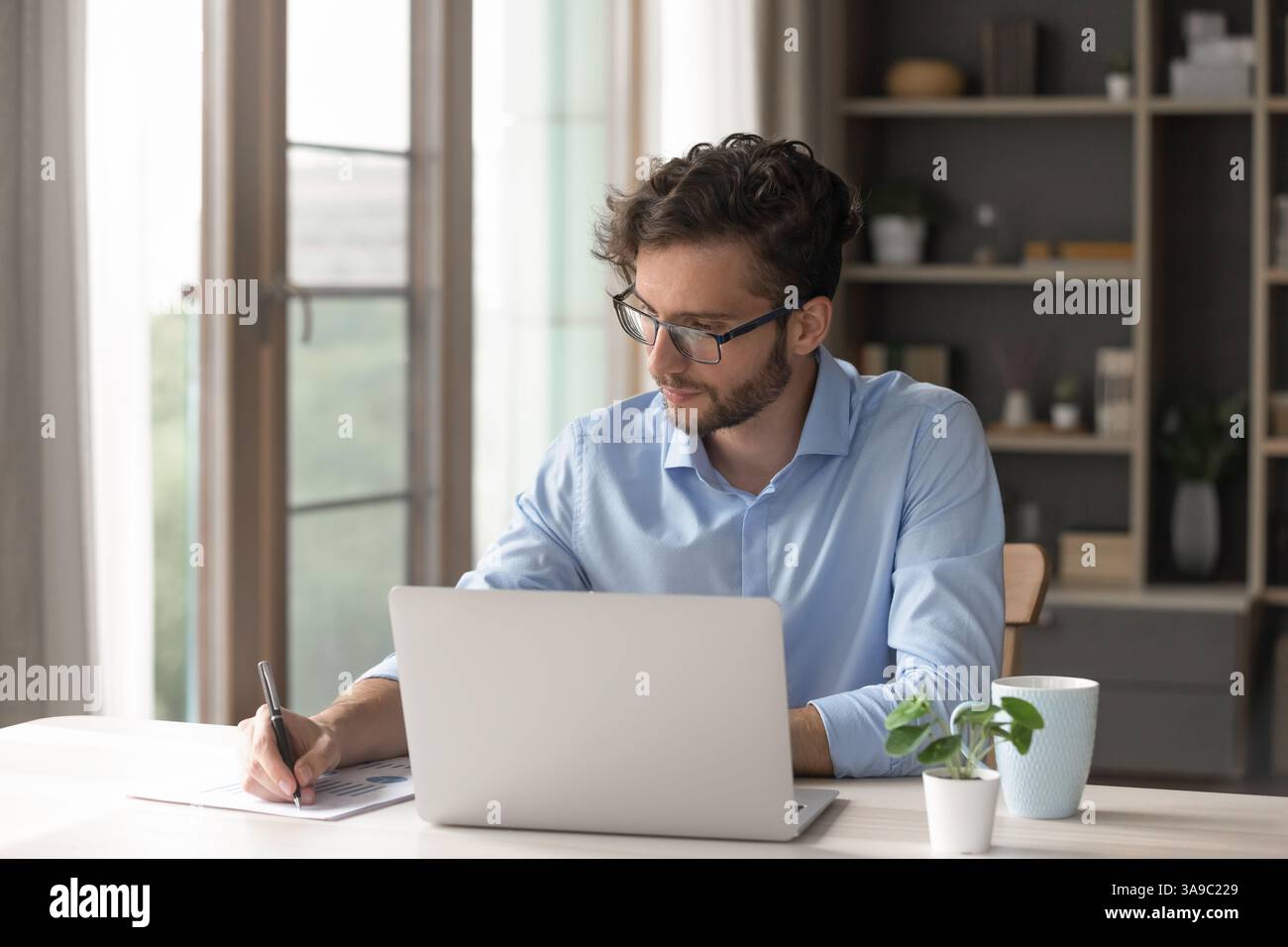 Young man working with notebook taking notes on paper documents Stock Photo