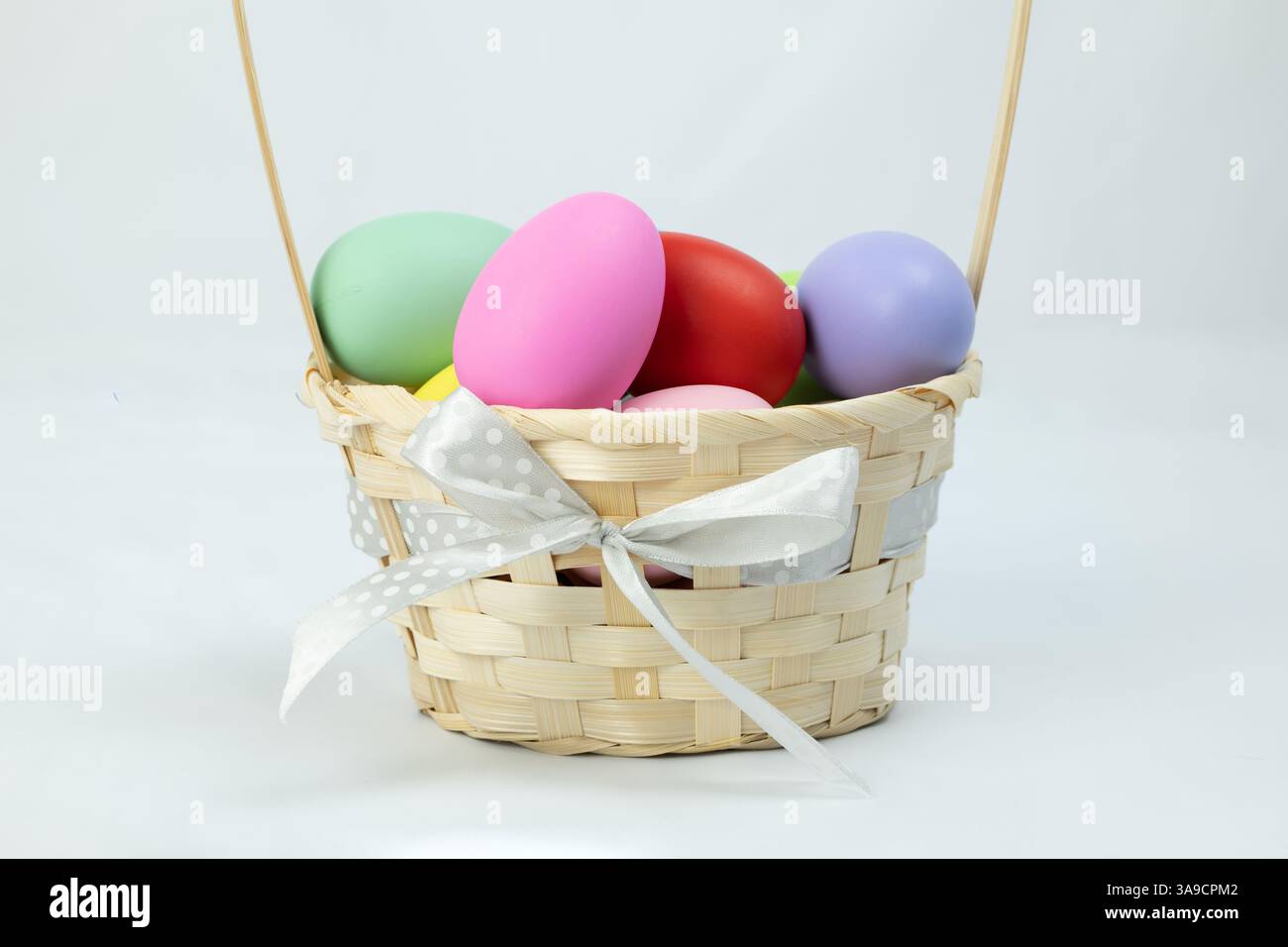 A basket with colorful easter eggs on white background, side view Stock Photo