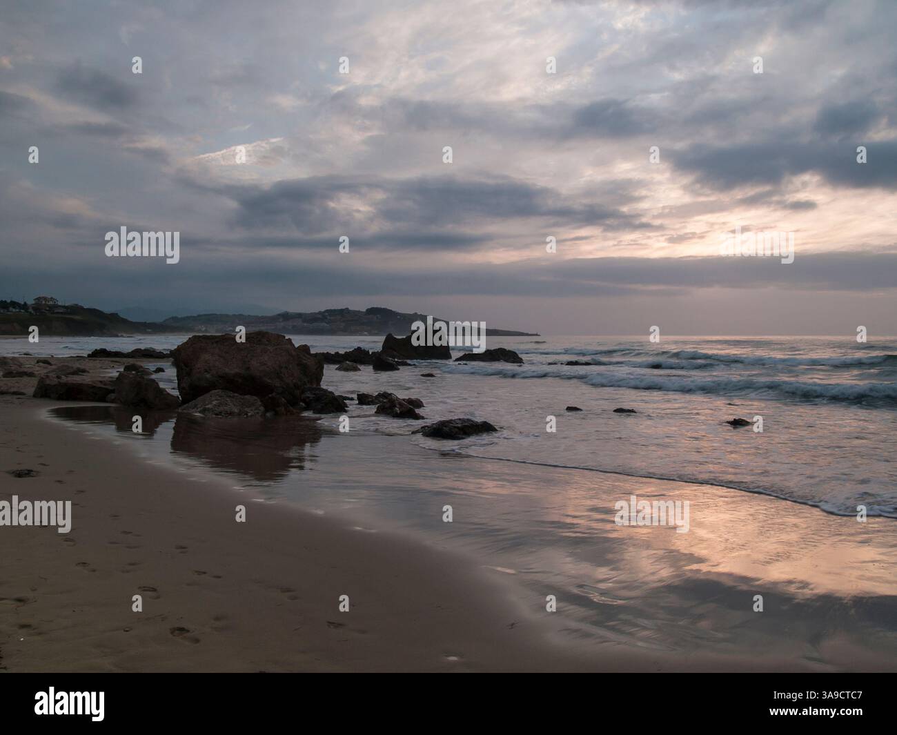 The beach lies quiet beneath a sky of brooding clouds, where the fading ...