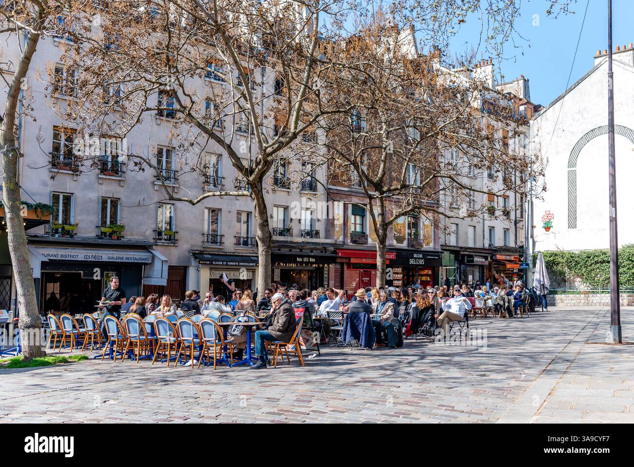 Paris, France, 03.27.2025. People enjoying the warm spring weather on outdoor patios in the 5th arrondissement of Paris. Springtime. Stock Photo