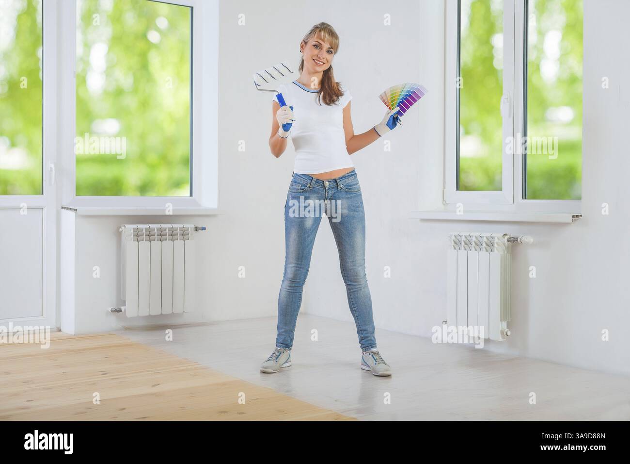 Happy female painter holding paintroller and color palette Stock Photo ...