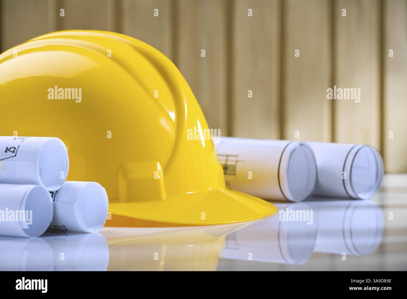 Yellow helmet and rolls of blueprints on table Stock Photo - Alamy