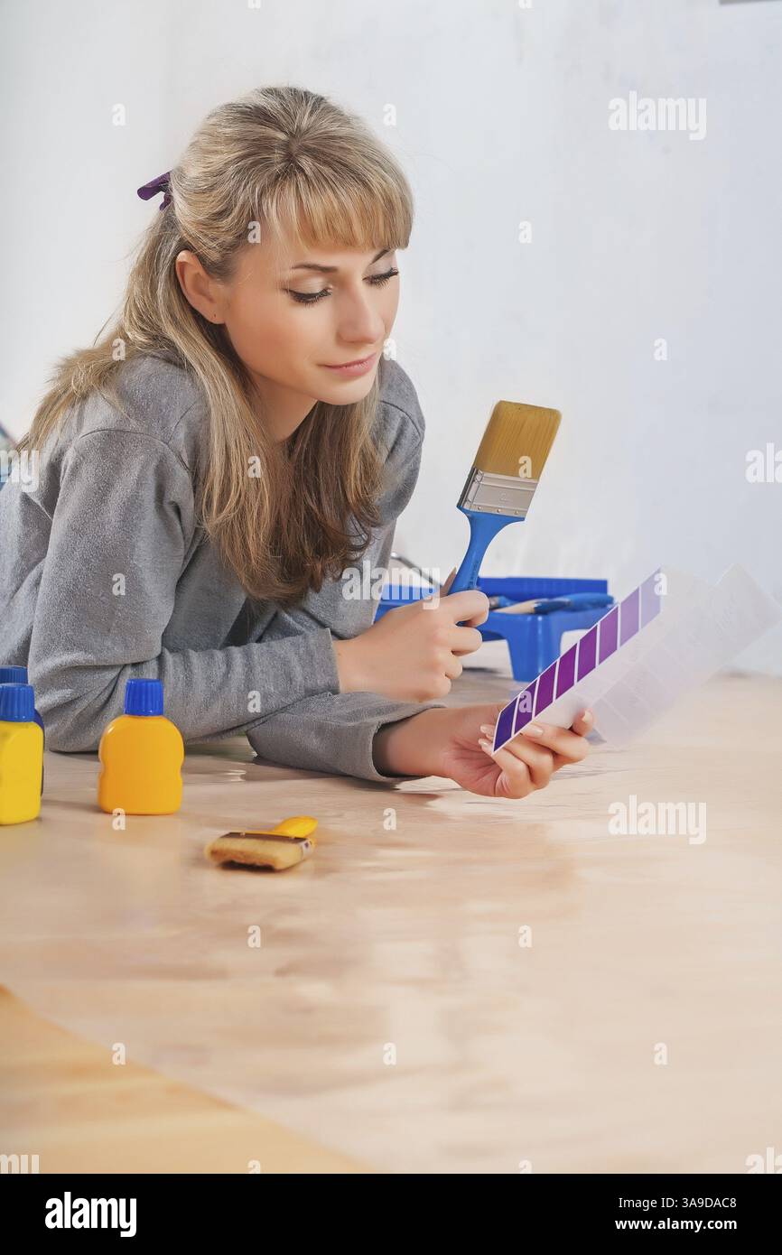 Beautiful caucasian female painter lies on floor holding paintbrush and ...