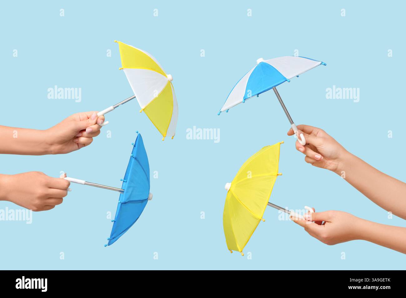 Female hands with different mini umbrellas on blue background Stock Photo