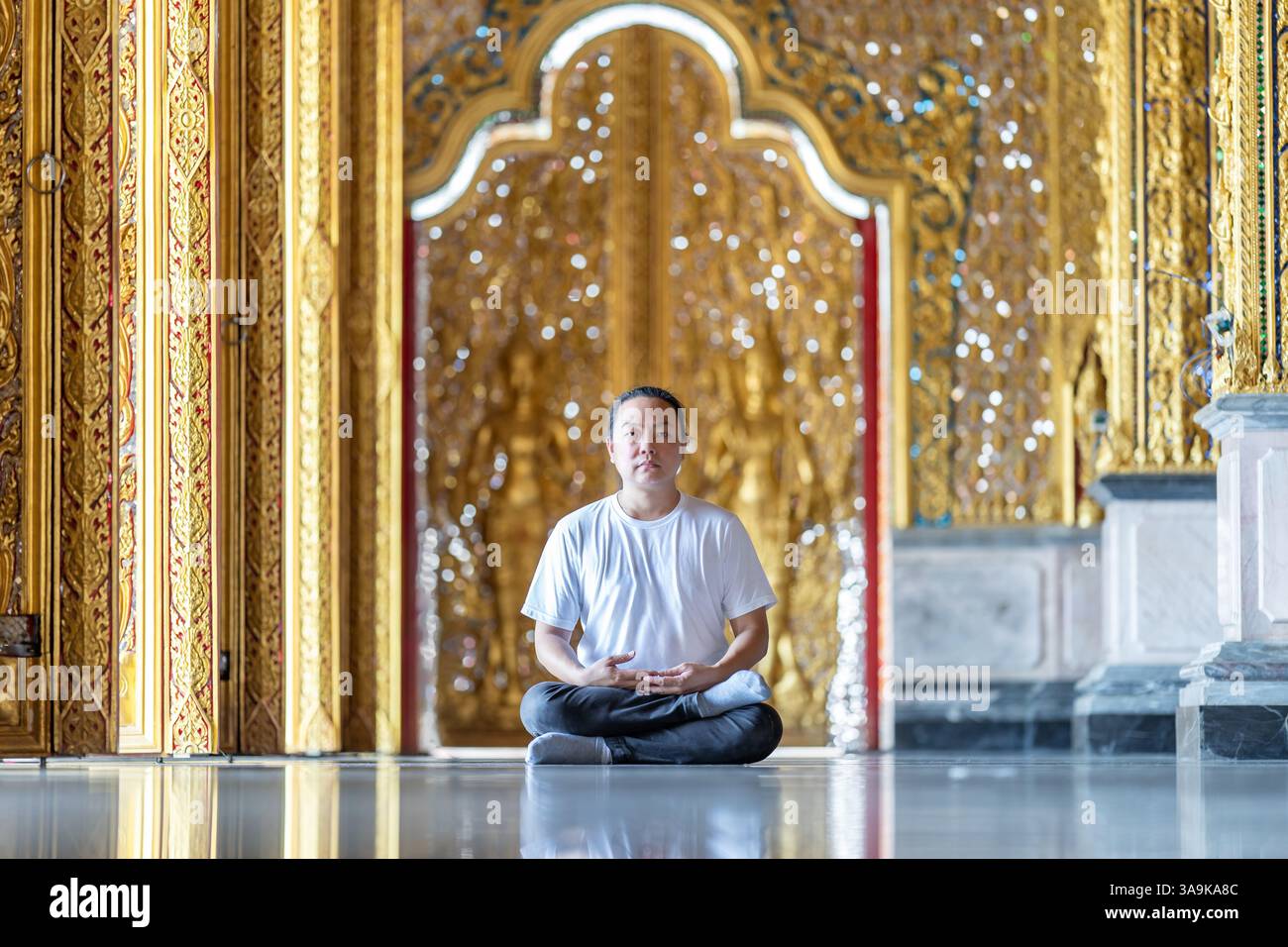 Asian Man meditates on the ground with reflection in the sunlight ...