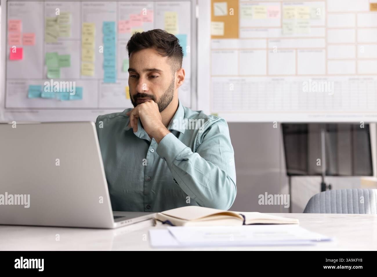 Focused Latin project manager man working at computer Stock Photo