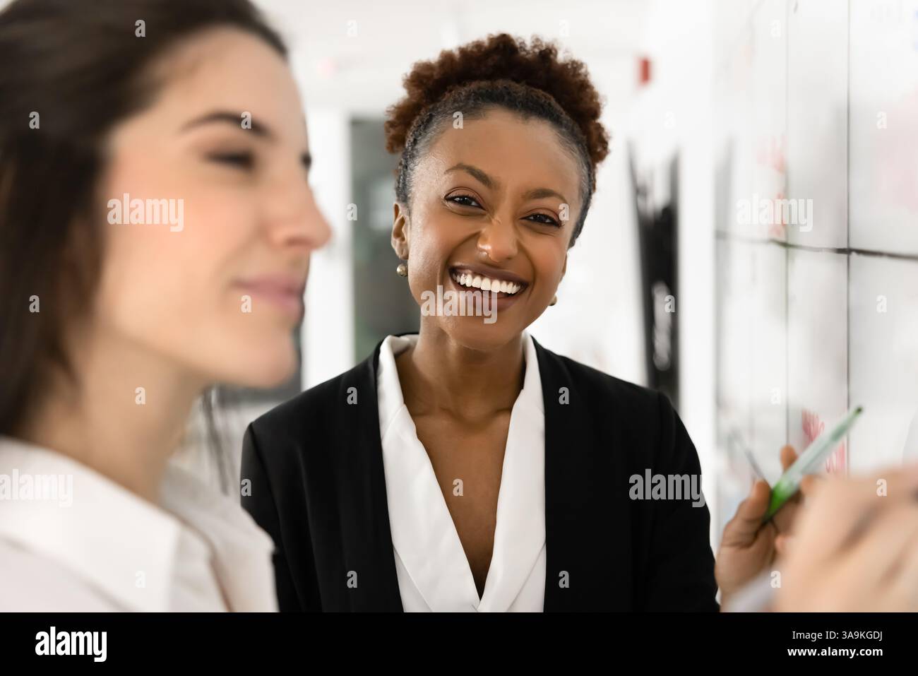 Cheerful beautiful young African businesswoman standing at whiteboard Stock Photo