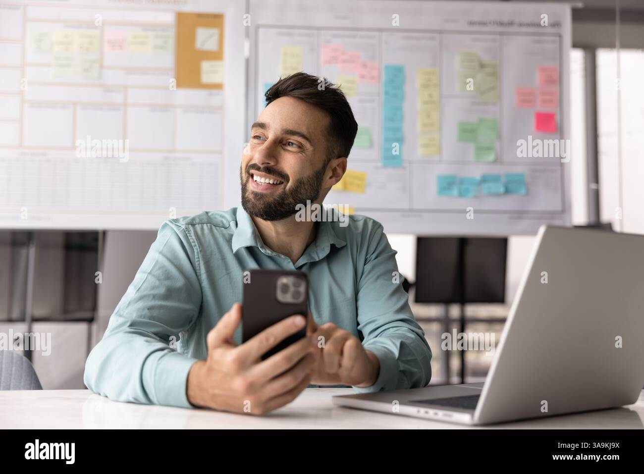 Happy project manager man using mobile phone at office workplace Stock Photo