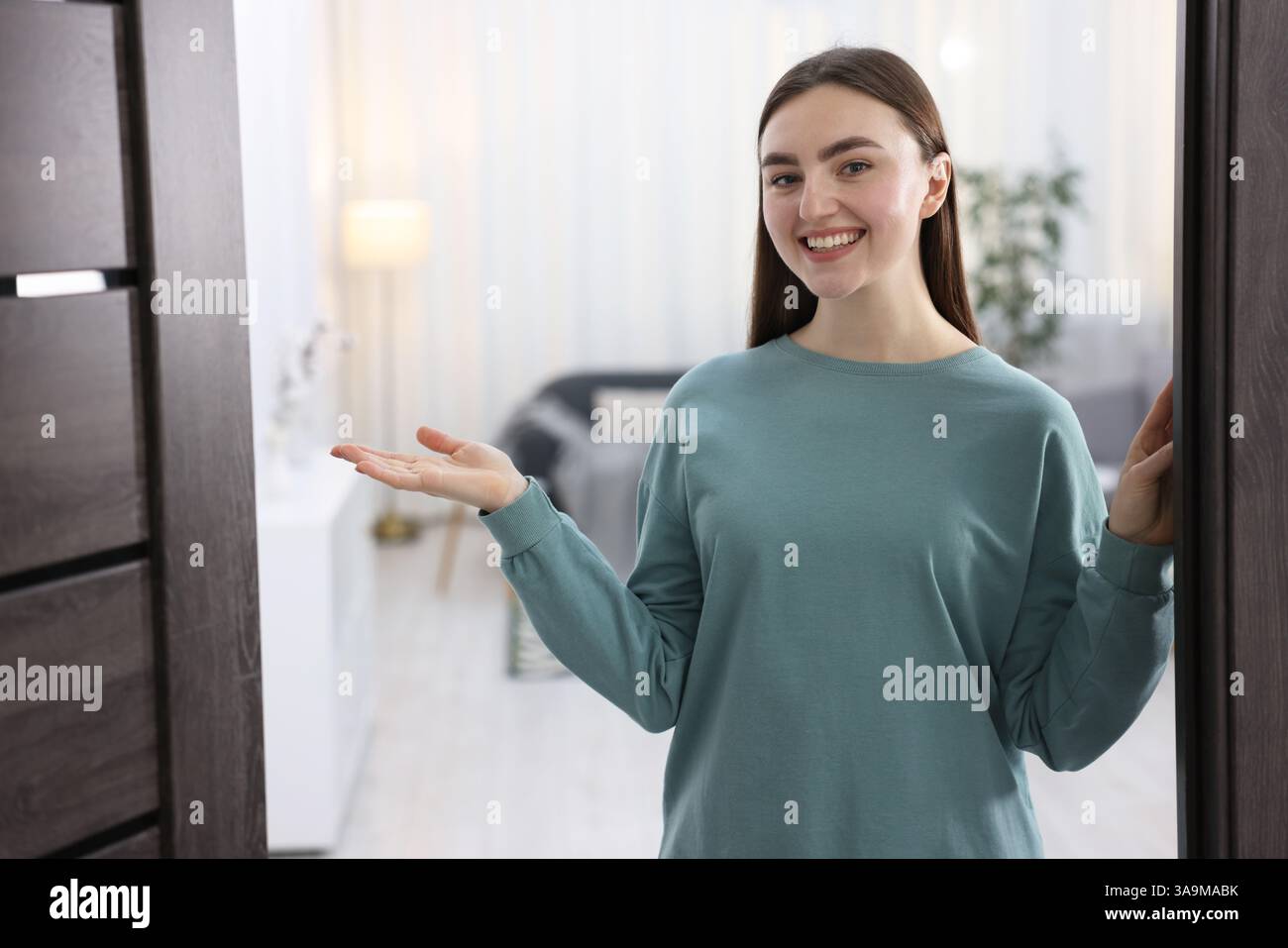 Cheerful woman welcoming guests to her apartment Stock Photo - Alamy