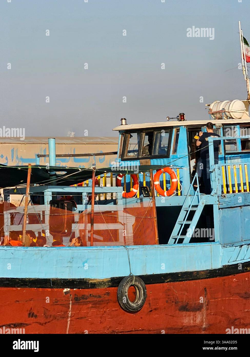 Option 1 (Focus on Detail): A detailed view of a boat's hull, showcasing its vibrant blue and red paint, along with essential nautical equipment like - Smartphone Captured Stock Image