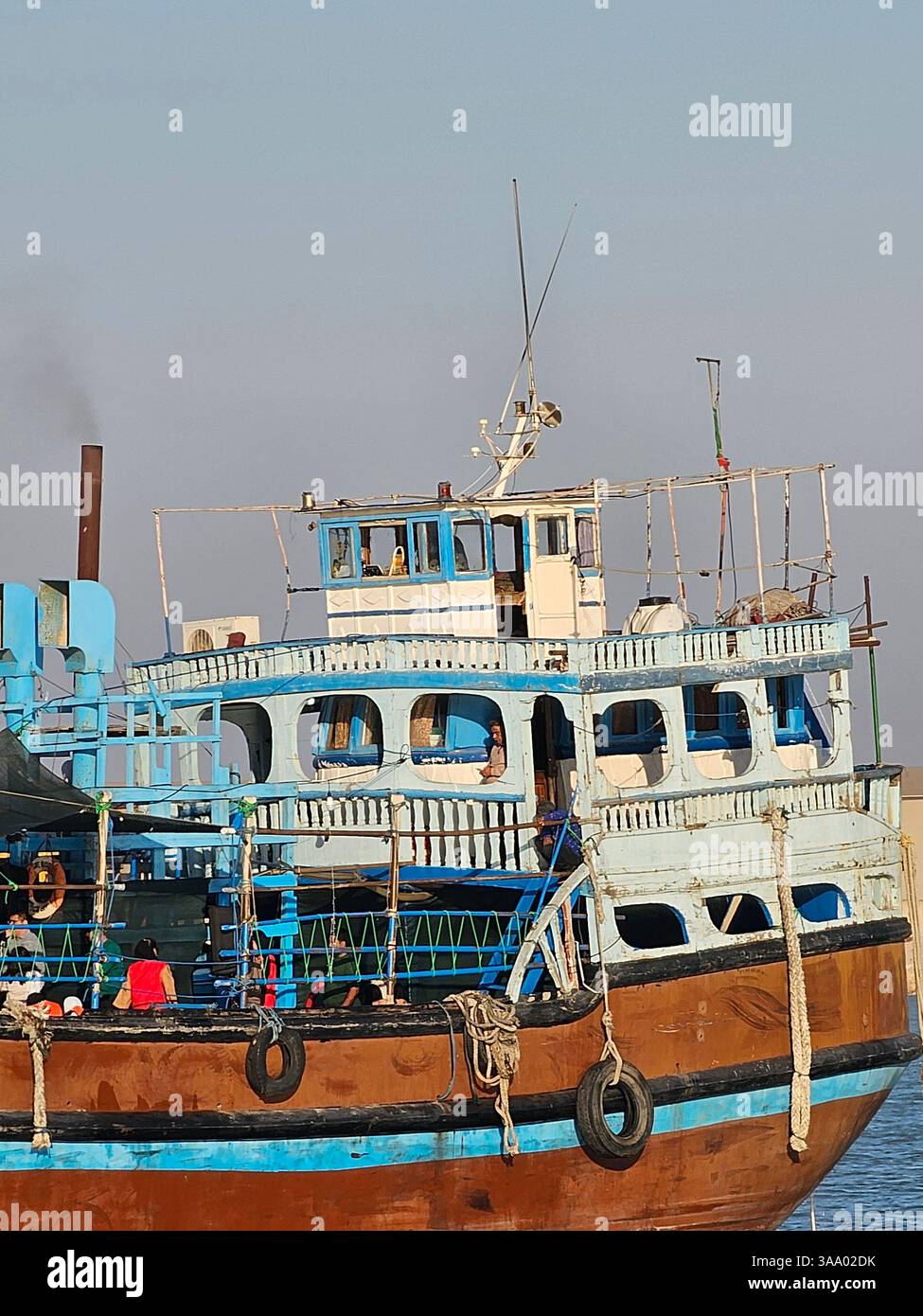 Option 1 (Focus on Detail): A detailed view of a boat's hull, showcasing its vibrant blue and red paint, along with essential nautical equipment like - Smartphone Captured Stock Image