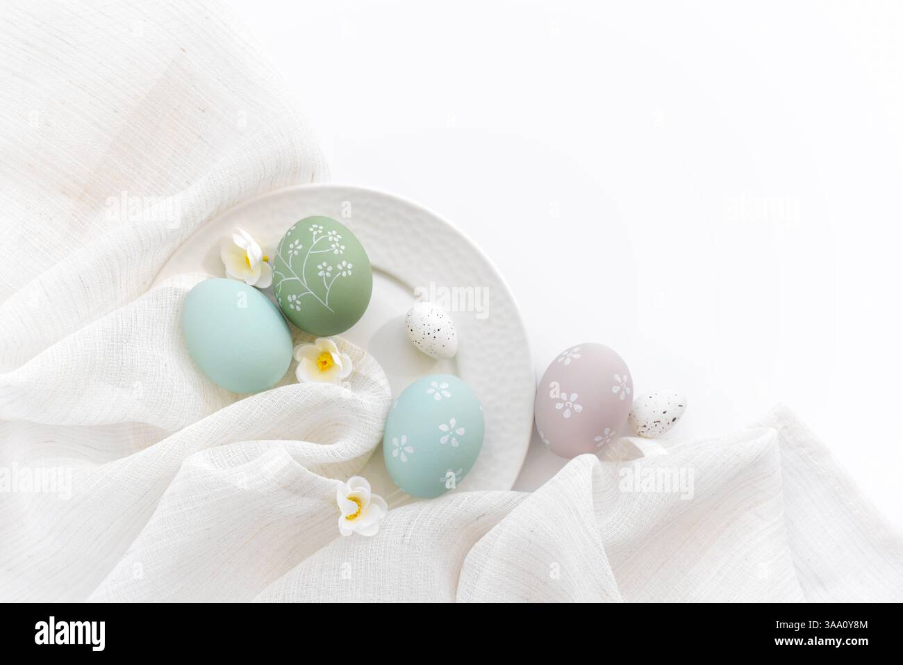 Stylish easter eggs and spring flowers on linen cloth on white table. Happy Easter concept. Top view Stock Photo