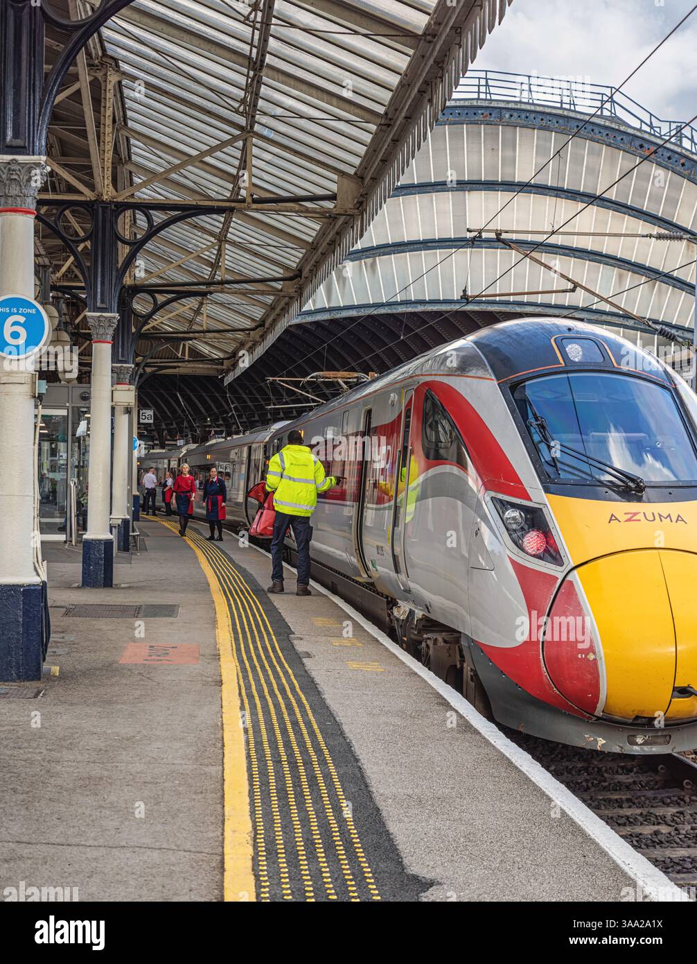 A train rests by a railway station platform with crew members on the ...