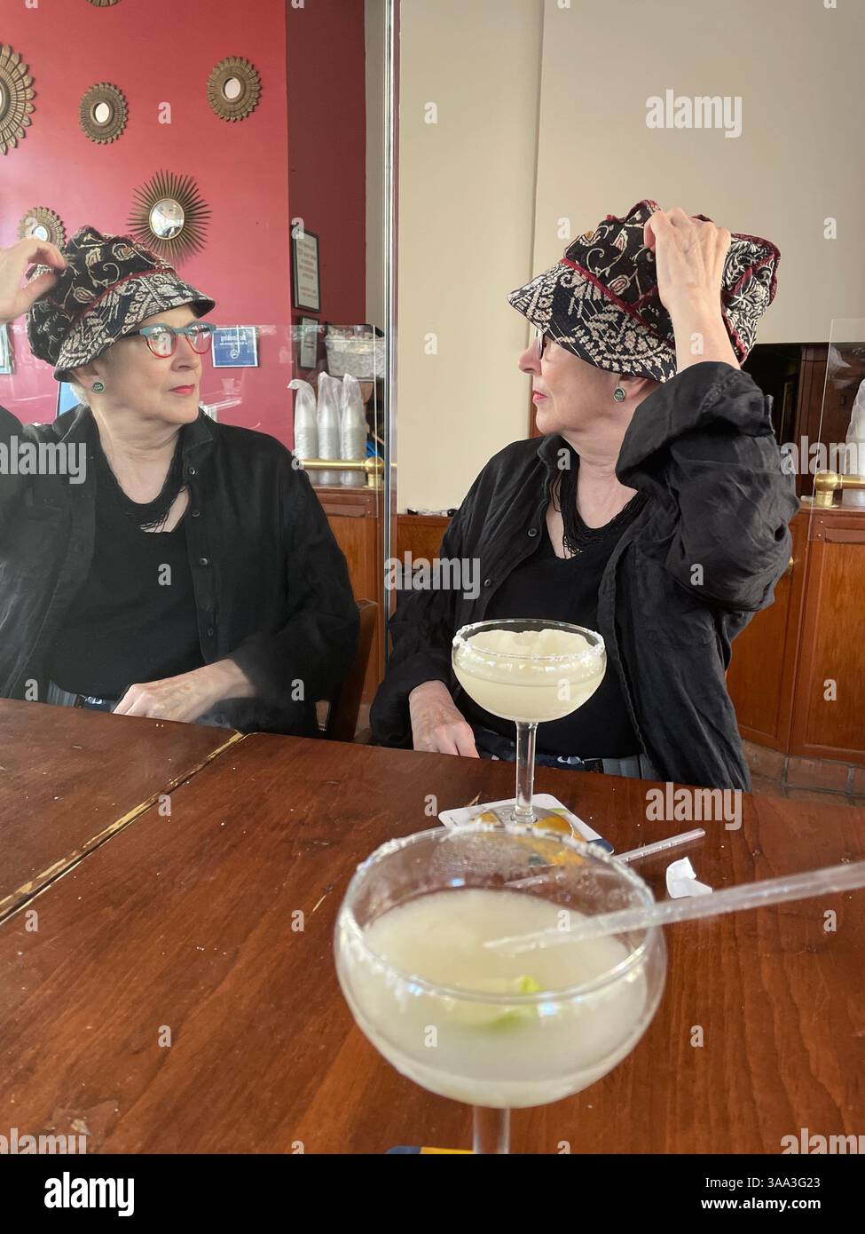 Stylish senior woman enjoying a margarita while looking in a mirror, El Rio Grande Tex-Mex restaurant, New York City, 2022, USA - Smartphone Captured Stock Image