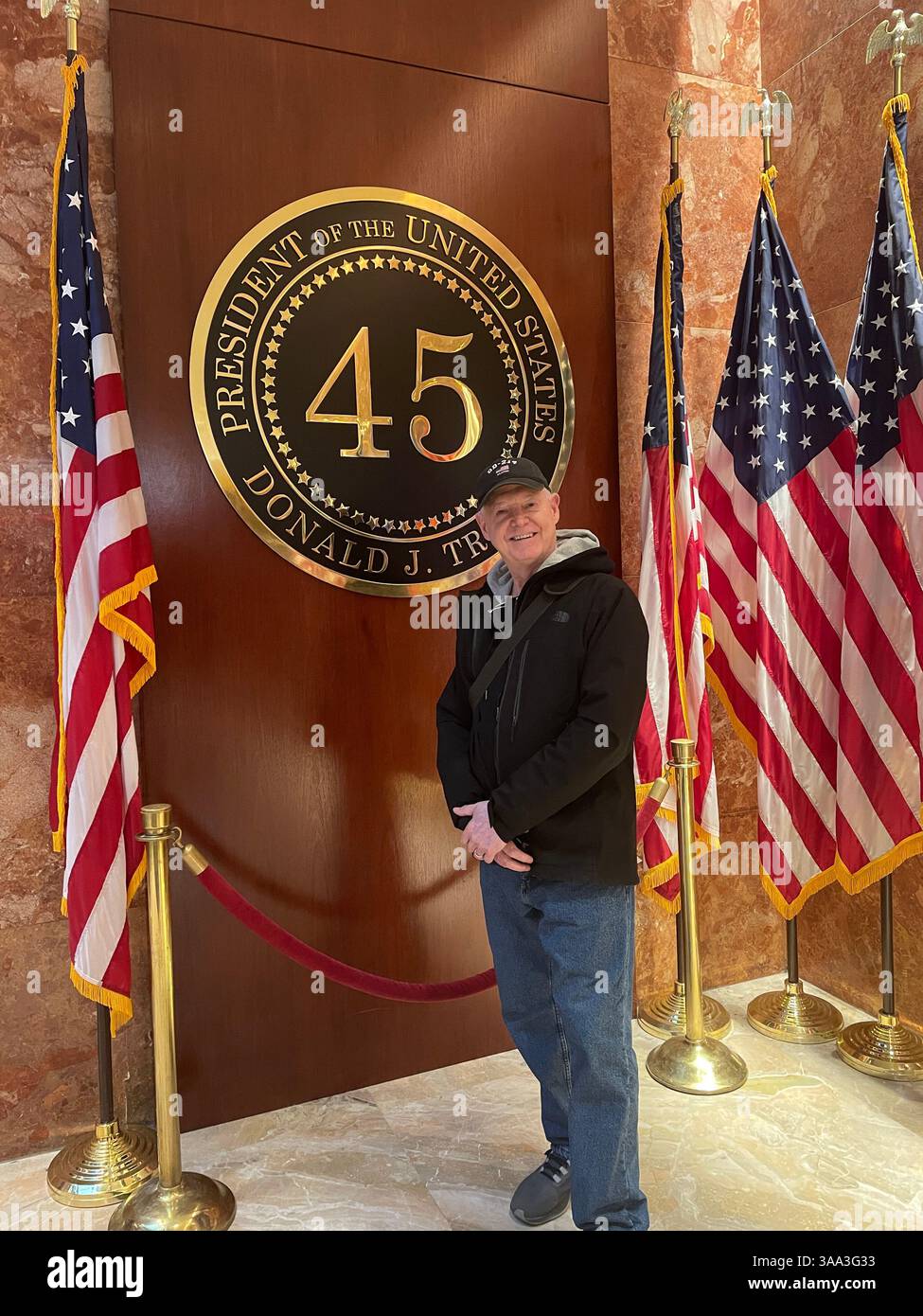 Handsome senior man posing for Photos at Trump's POTUS Display and Flags, Trump Tower, 2024, NYC, USA - Smartphone Captured Stock Image