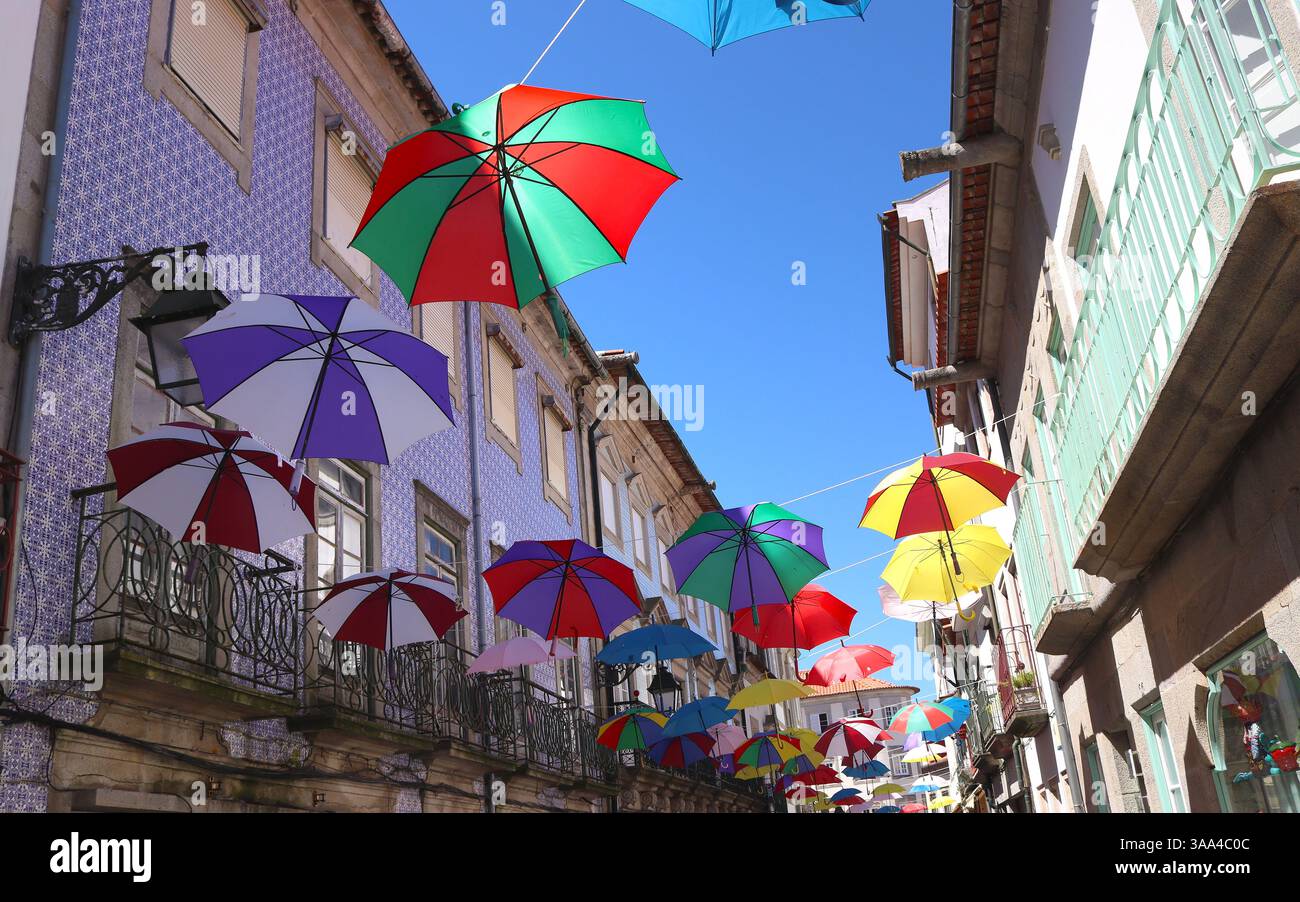 Colorful umbrellas over alley in typical architectural style using fixtures of buildings with azulejos, Viana do Castelo, Portugal Stock Photo