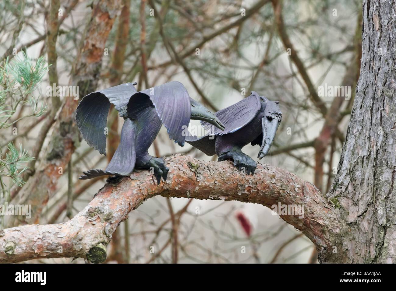 Fake metal bird imitation to repeal real birds. Metal artistic statue on the tree. Stock Photo
