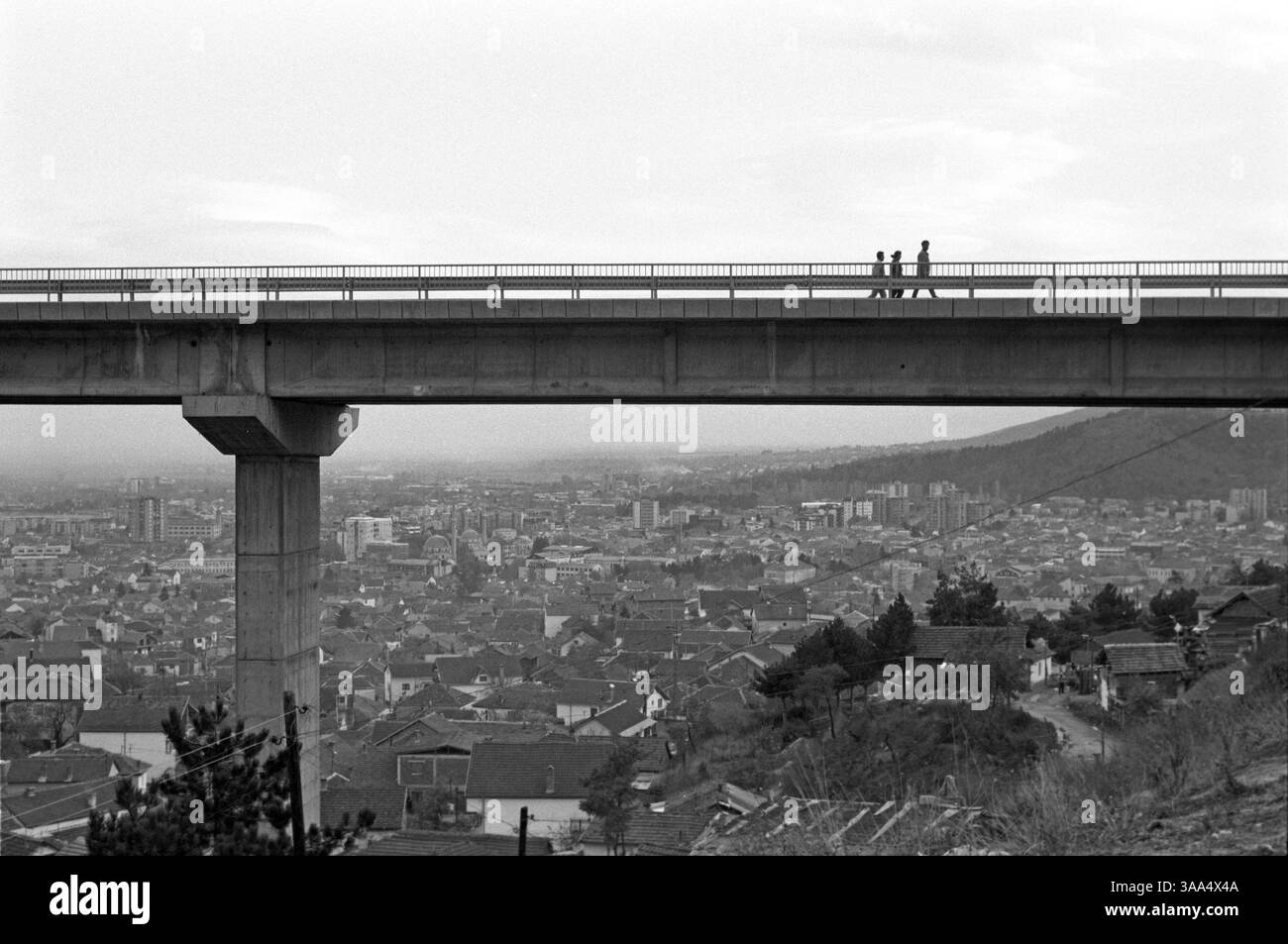 Jan 30, 2007; Bitola, MACEDONIA; The Roma mostly live as they have always done in Europe, in distinct neighbourhoods on the edges of towns and cities. Here three Roma walk home along a bridge that passes over the illegal settlement of Bair, and looks down on the city of Bitola below. Roma communities are segregated economically, socially, physically and psychologically. The Roma stay on the fringes, selling things in the old bazaar, or waiting for jobs by the roadside. The people that we know as the Roma or Gypsies today, were originally part of an army in India that was recruited from the low Stock Photo