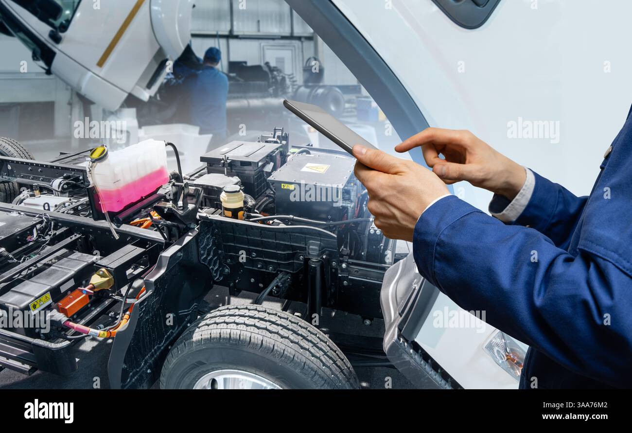 Serviceman with digital tablet next to electric truck. Electric vehicles maintenance.. Stock Photo