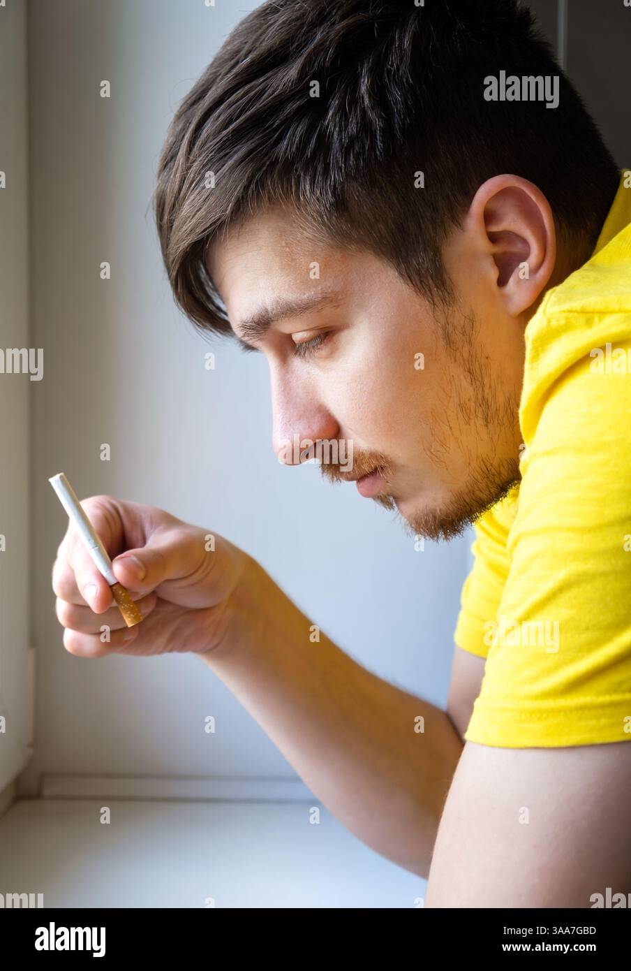 Pensive Young Man with a Cigarette in the Doubt Stock Photo