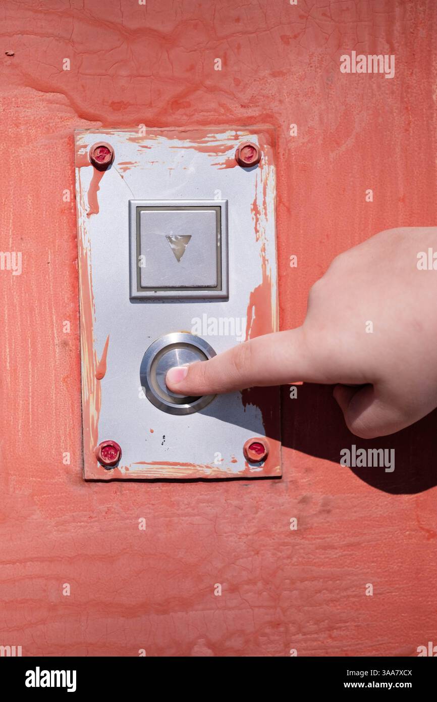 Close up hand pushing button on red door Stock Photo