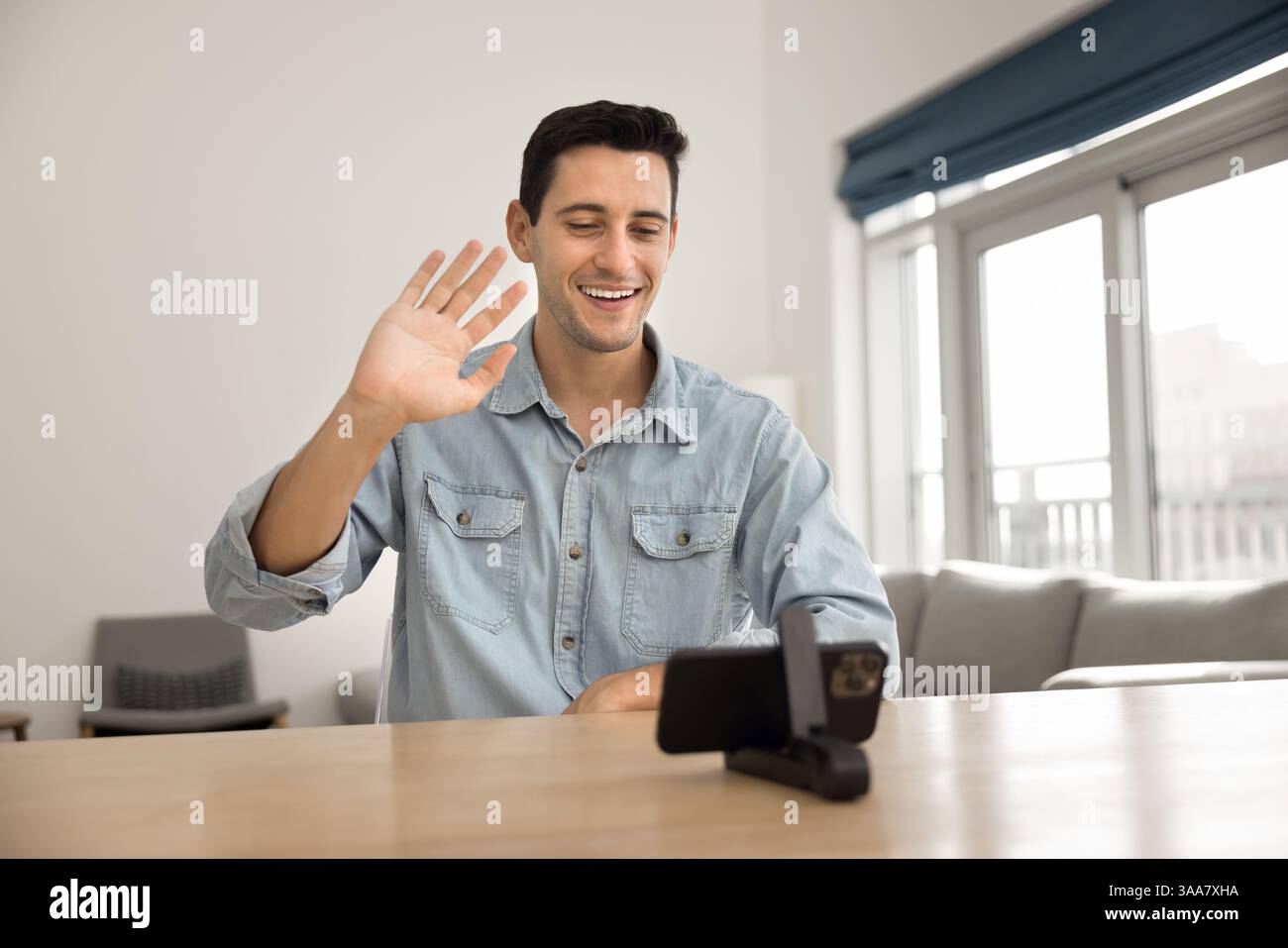 Young man participating in virtual meeting or videocall using smartphone Stock Photo