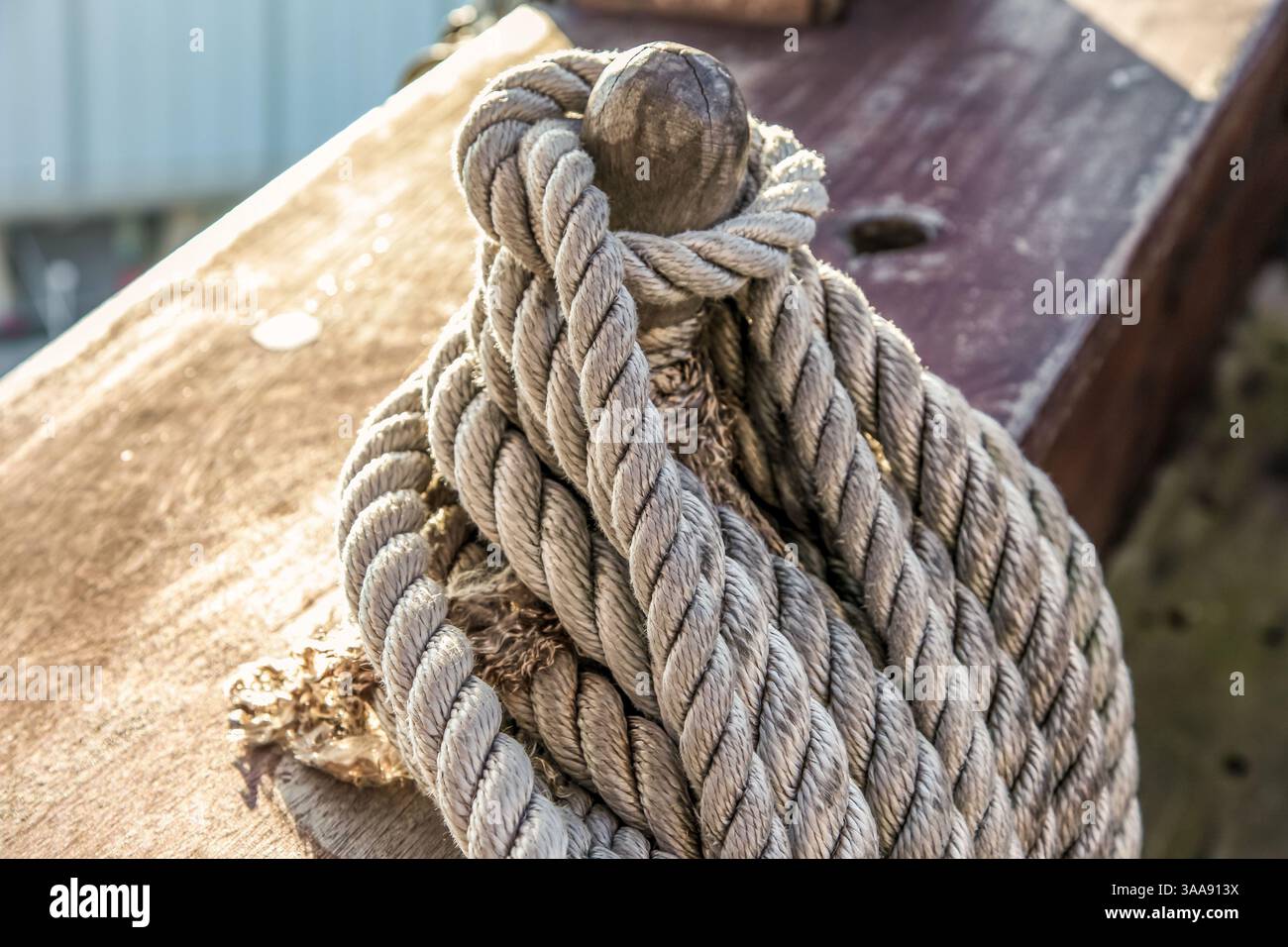 A rope is tied to a wooden post. The rope is frayed and has a knot in ...