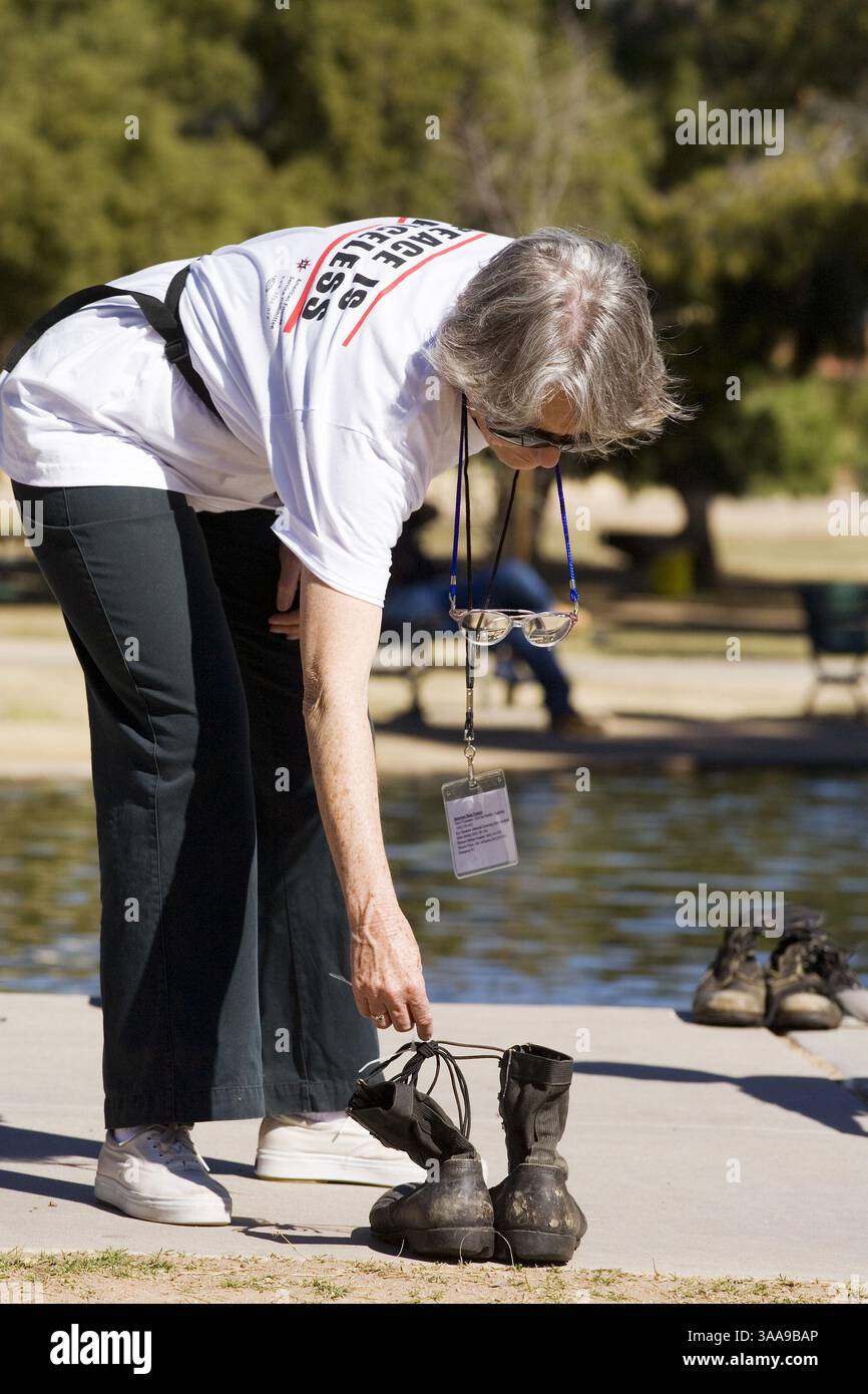Feb 17, 2007 - Phoenix, AZ, USA - SHEILA RYAN, from Phoenix, AZ, looks for boots representing National Guard soldiers from Iowa (her home state) at the Eyes Wide Open exhibit in Encanto Park in Phoenix, AZ. Eyes Wide Open is a national project created by the American Friends Service Committee. It is meant to be a living memorial to the military personnel and civilians killed in Iraq. More than 400 pairs of military style boots are laid out in the park to represent members of the National Guard killed in Iraq. There are also shoes set out to represent Iraqi civilians killed in the war. (Credit Stock Photo