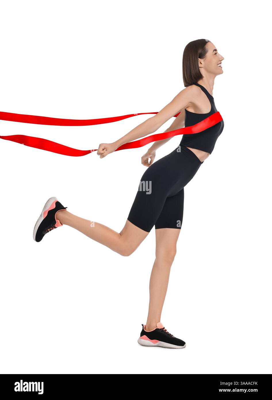 Happy sportswoman crossing red finish line ribbon on white background ...