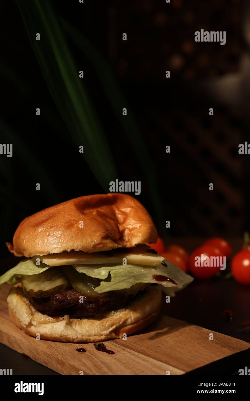hamburger on a board against the background of ripe cherry tomatoes, in a restaurant. Stock Photo