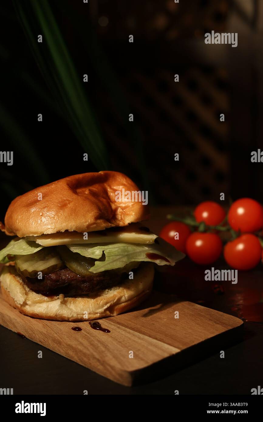hamburger on a board against the background of ripe cherry tomatoes, in a restaurant. Stock Photo