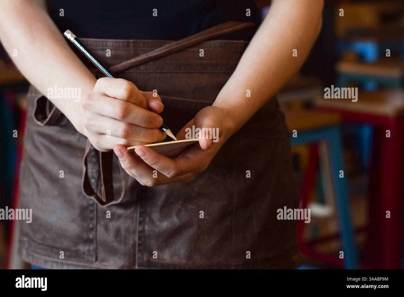 Female server writing down customer order on note pad Stock Photo