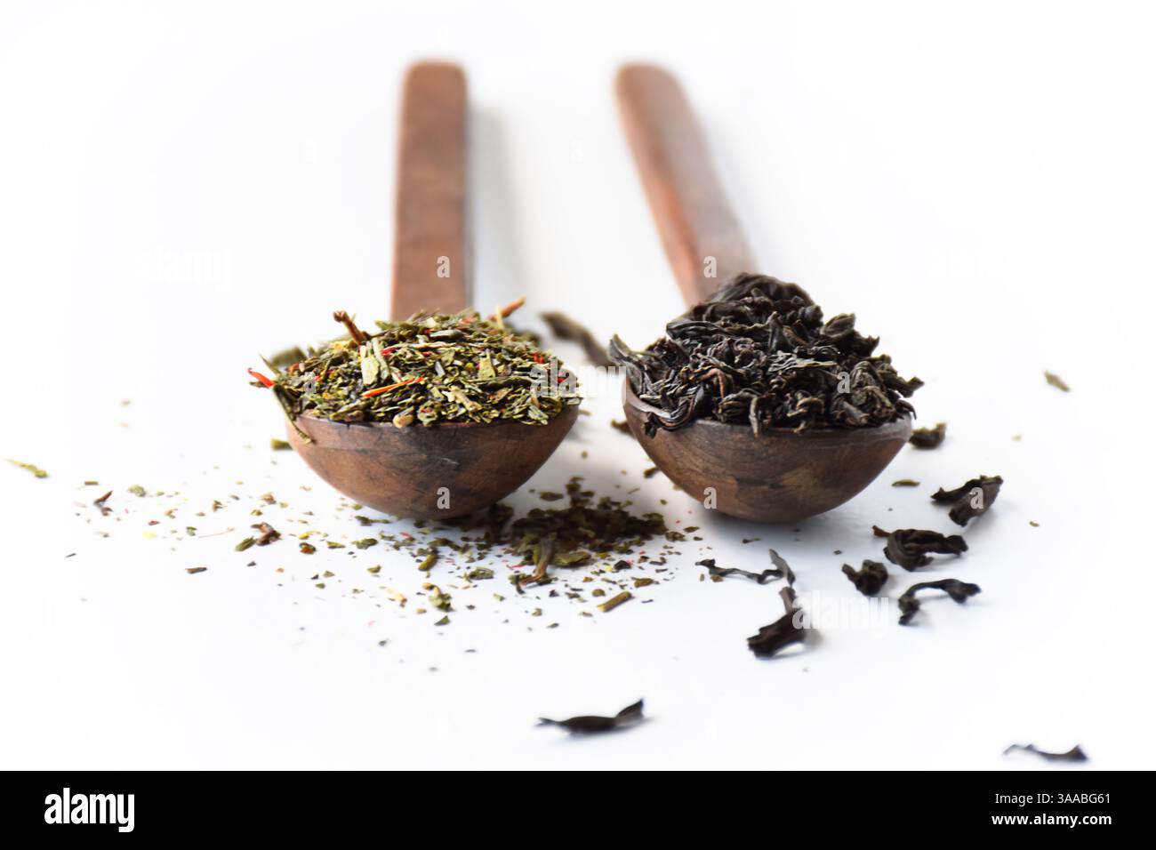 Black and green loose leaf teas in wooden spoons isolated on white background Stock Photo