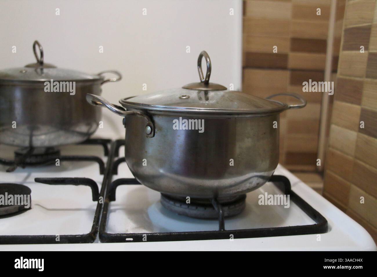 A metal saucepan stands on a gas stove. Kitchen, cooking. Stock Photo