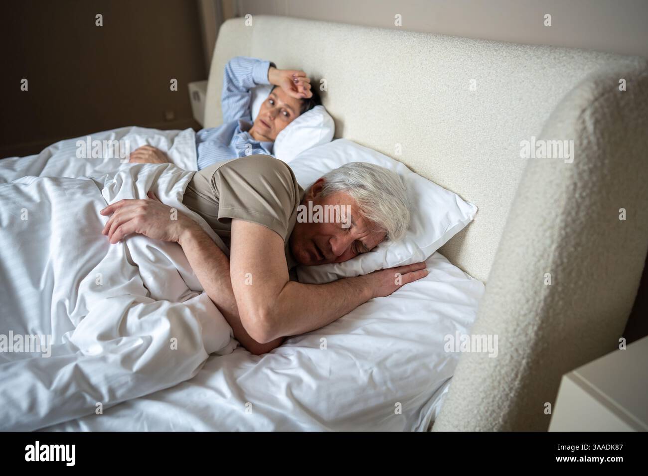 Upset angry wife lies in bed after argument watching husband who fell ...