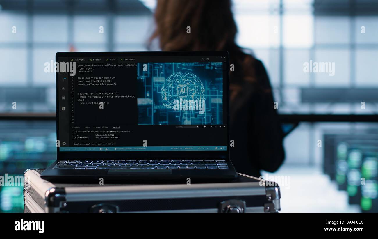 Laptop in front of data center engineers in background deploying artificial intelligence tools. AI coding on notebook screen next to technicians inspecting server clusters, camera A close up Stock Photo
