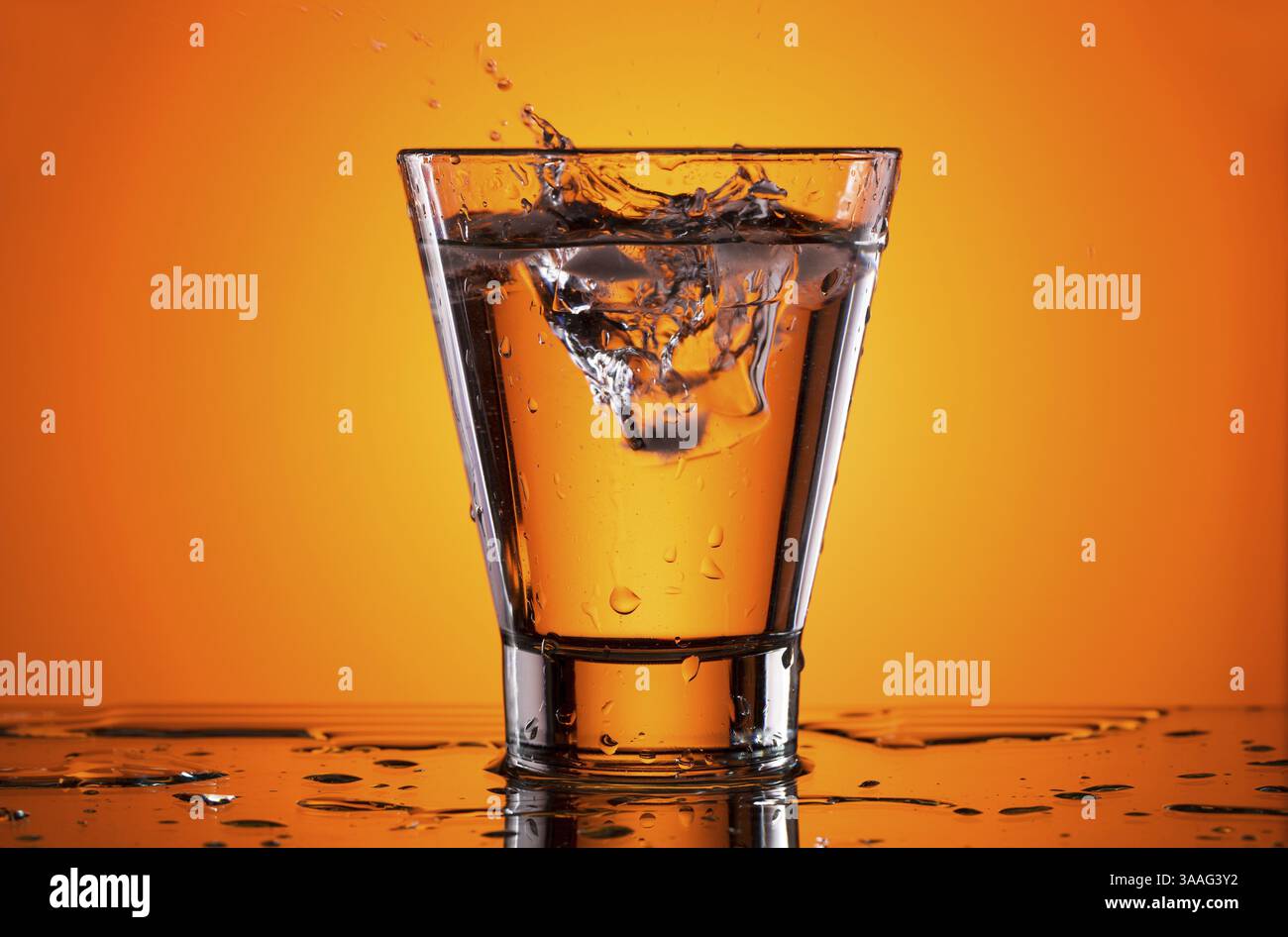 Ice in a glass of water. Orange background Stock Photo