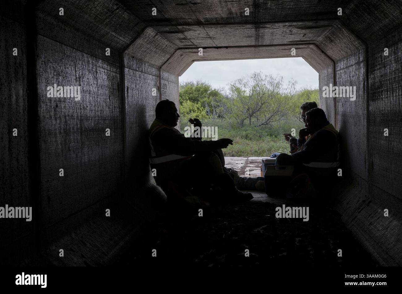 March 2, 2018 - Los Fresnos, TX, USA - Construction workers George Hernandez, left, Merced Doria, far right, and Pablo Ruiz eat lunch inside of an animal crossing on March 2, 2018, in Los Fresnos, Texas. Animal crossings have been installed in certain areas in a bid to prevent ocelots and other animals from being hit and killed by cars. (Credit Image: © Ana Ramirez/TNS via ZUMA Wire) Stock Photo