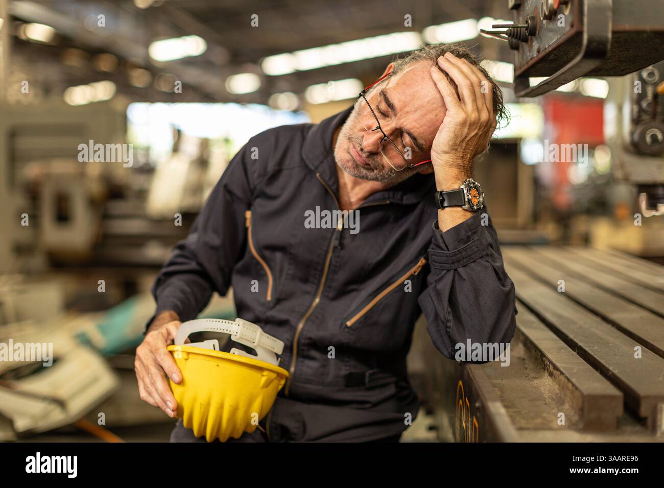 Senior engineer worker tired exhausted sleep nap at work in heavy industry factory. Stock Photo