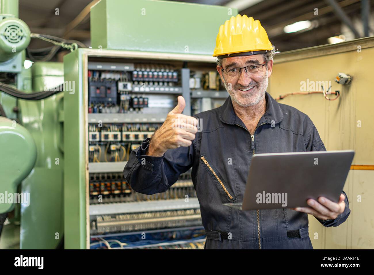 Senior Professional Electrician engineer supervisor happy smiling work in heavy industry service machine electricity wire cable with laptop computer. Stock Photo
