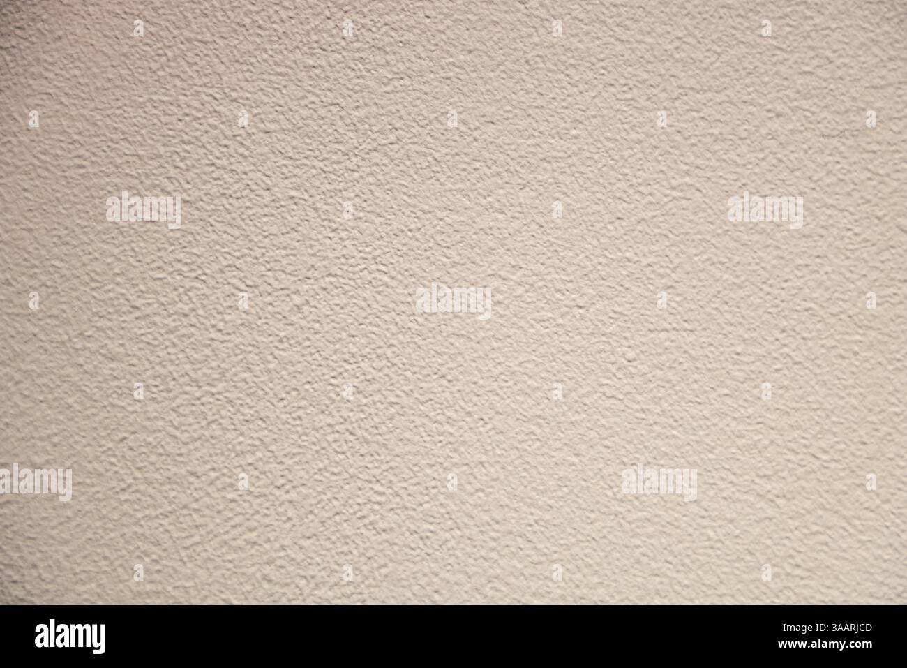 Close-up of a uniform textured beige wall with a stucco surface. The uniform pattern creates a neutral and minimalistic background suitable for design Stock Photo