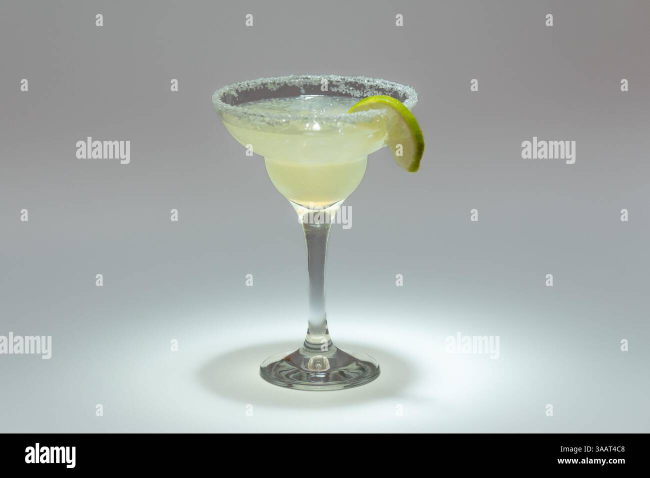 Classic Margarita Cocktail Garnished with Lime Slice and Salt Rim in Elegant Stemmed Glass. Stock Photo
