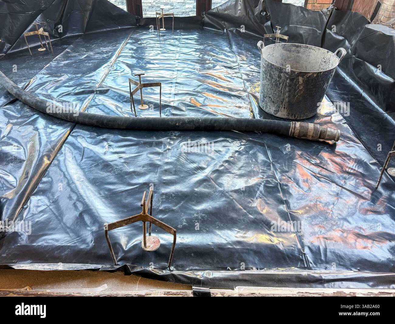 Plastic membrane , levelling equipment and hose on the floor of a new conservatory ready for concrete screed to be pumped into the area. No people. - Smartphone Captured Stock Image